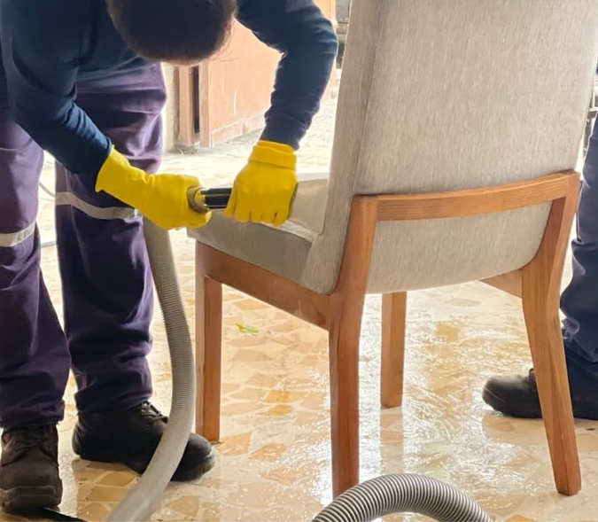 Limpieza de sillas: técnico con guantes lavando el asiento de una silla tapizada